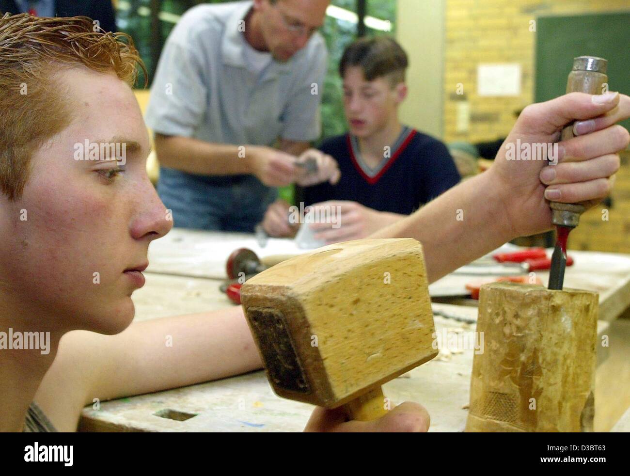 (dpa) - Under the motto 'Coole Schule' (cool school) the two 15-year-old students Alexander Loeffler (L) and Johann Tews work with social worker Severin Daldrup in a workshop of a secondary school in Belm, Germany, 3 July 2003. The project was created for notorious truants and to make them go back t Stock Photo
