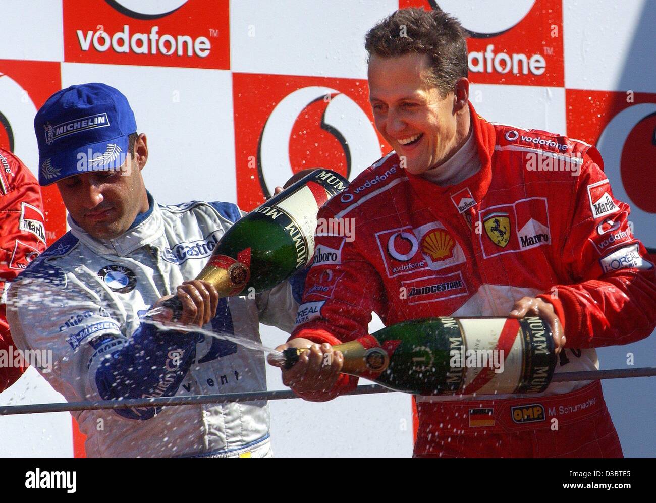 (dpa) - The winner of the Grand Prix of Italy, German formula one pilot Michael Schumacher of Ferrari (R), and second-placed Colombian Juan Pablo Montoya of BMW-Williams (L) splash champagne on the podium on the race track in Monza, Italy, 14 September 2003. Schumacher leads the overall standings wi Stock Photo