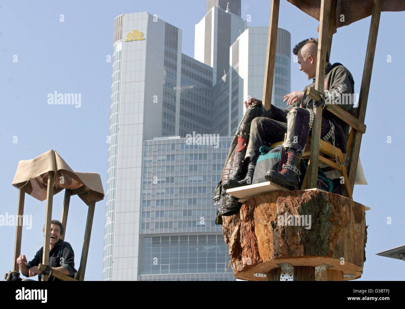 (dpa) - Two men are sitting in chairs on wooden poles, in the background the Commerzbank tower in Frankfurt, Germany, 15 September 2003. The event of the 'Church of Fear' is staged by theatre and film director Christoph Schlingensief and lasts until 20 September. Seven people who are workless, homel Stock Photo