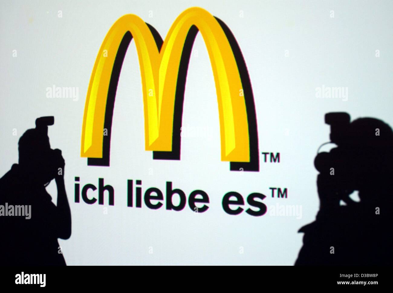 (dpa) - Two journalists take a photo of the new logo of the fast food chain McDonald's during a press conference in Munich, 2 September 2003. The slogan 'ich liebe es' ('i'm lovin' it') will soon make its way into the vocabulary of McDonald's customers in more than 100 countries as the Golden Arches Stock Photo