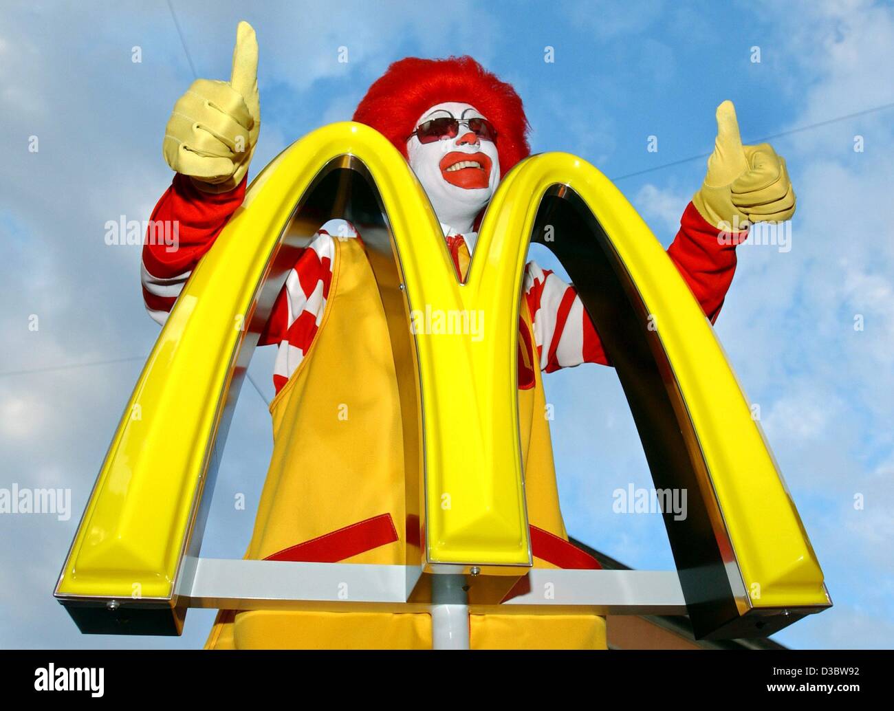 (dpa) - 'Ronald McDonald' poses behind the logo of the fast food chain McDonald's during a press conference in Munich, 2 September 2003. The slogan 'ich liebe es' ('i'm lovin' it') will soon make its way into the vocabulary of McDonald's customers in more than 100 countries as the Golden Arches laun Stock Photo