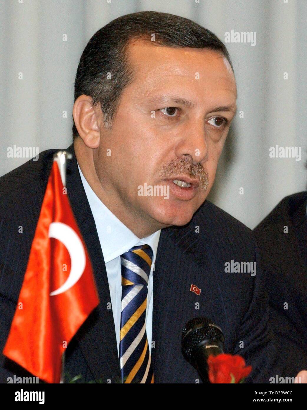 (dpa) - Turkish Prime Minister Recep Tayyip Erdogan sits next to a Turkish flag as he visits a Turkish neighbourhood club in Berlin, 2 September 2003. Stock Photo