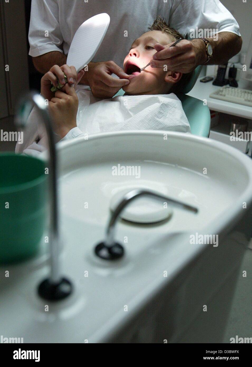 (dpa) - A dentist examines the teeth of a boy in a practice in Magdeburg, Germany, 18 August 2003. The envisaged healthcare reform of the German government will result in deep cuts in the health and welfare systems. Germany's expensive healthcare system which is funded entirely by levies on payrolls Stock Photo