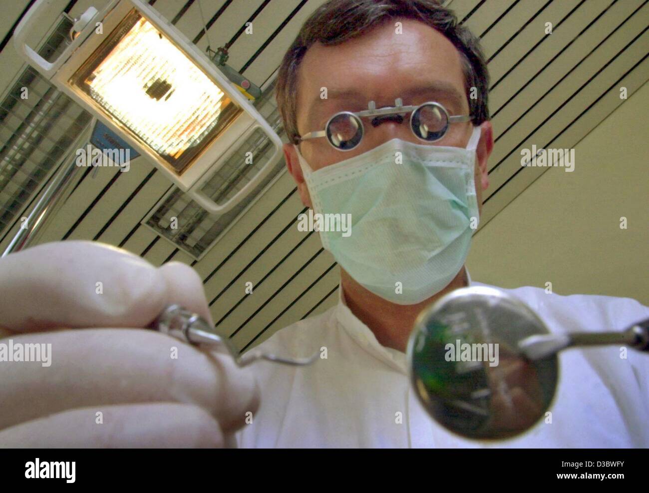 (dpa) - Dentist Rainer Baldauf simulates an examination of teeth while wearing a mask and magnifying glasses in a practice in Rimpar, Germany, 30 July 2003. The envisaged healthcare reform of the German government will result in deep cuts in the health and welfare systems. Germany's expensive health Stock Photo
