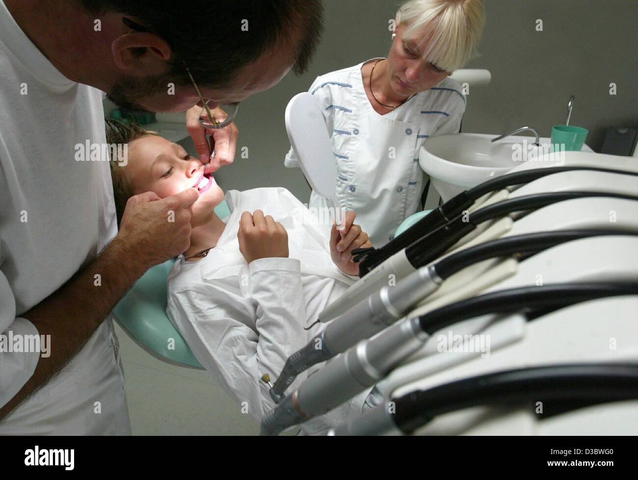 (dpa) - A dentist examines the teeth of a boy in a practice in Magdeburg, Germany, 18 August 2003. The envisaged healthcare reform of the German government will result in deep cuts in the health and welfare systems. Germany's expensive healthcare system which is funded entirely by levies on payrolls Stock Photo