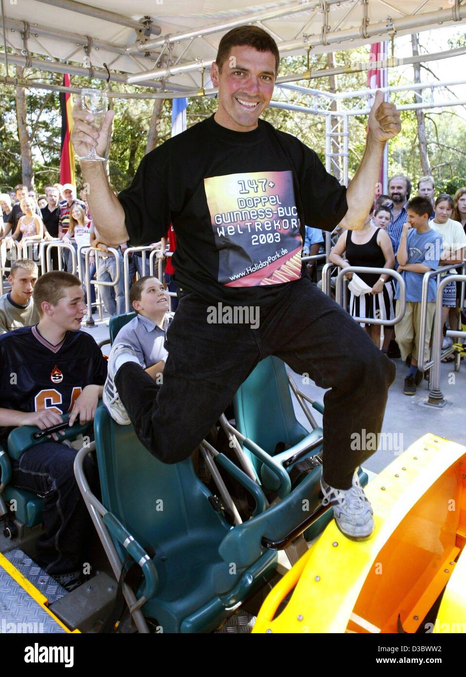 (dpa) - US American Richard Rodriguez poses with a glass of champagne on the rollercoaster in the amusement park Holiday Park in Hassloch, Germany, 26 August 2003. His t-shirt reads 'double Guinness book world record'. The highschool teacher from Chicago broke the world record in continous rollercoa Stock Photo