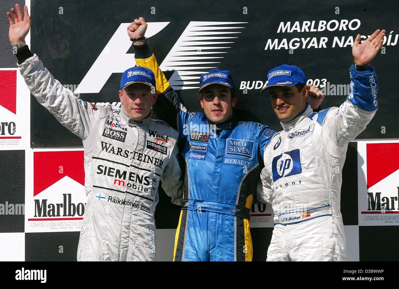 (dpa) - Spain's Fernando Alonso of Renault (C) is flanked by second placed Finnish Kimi Raeikkoenen (L) of McLaren-Mercedes and third placed Colombian Juan Pablo Montoya of BMW-Williams after the Hungarian Grand Prix in Budapest, 24 August 2003. Alonso made Formula One history by becoming the younge Stock Photo