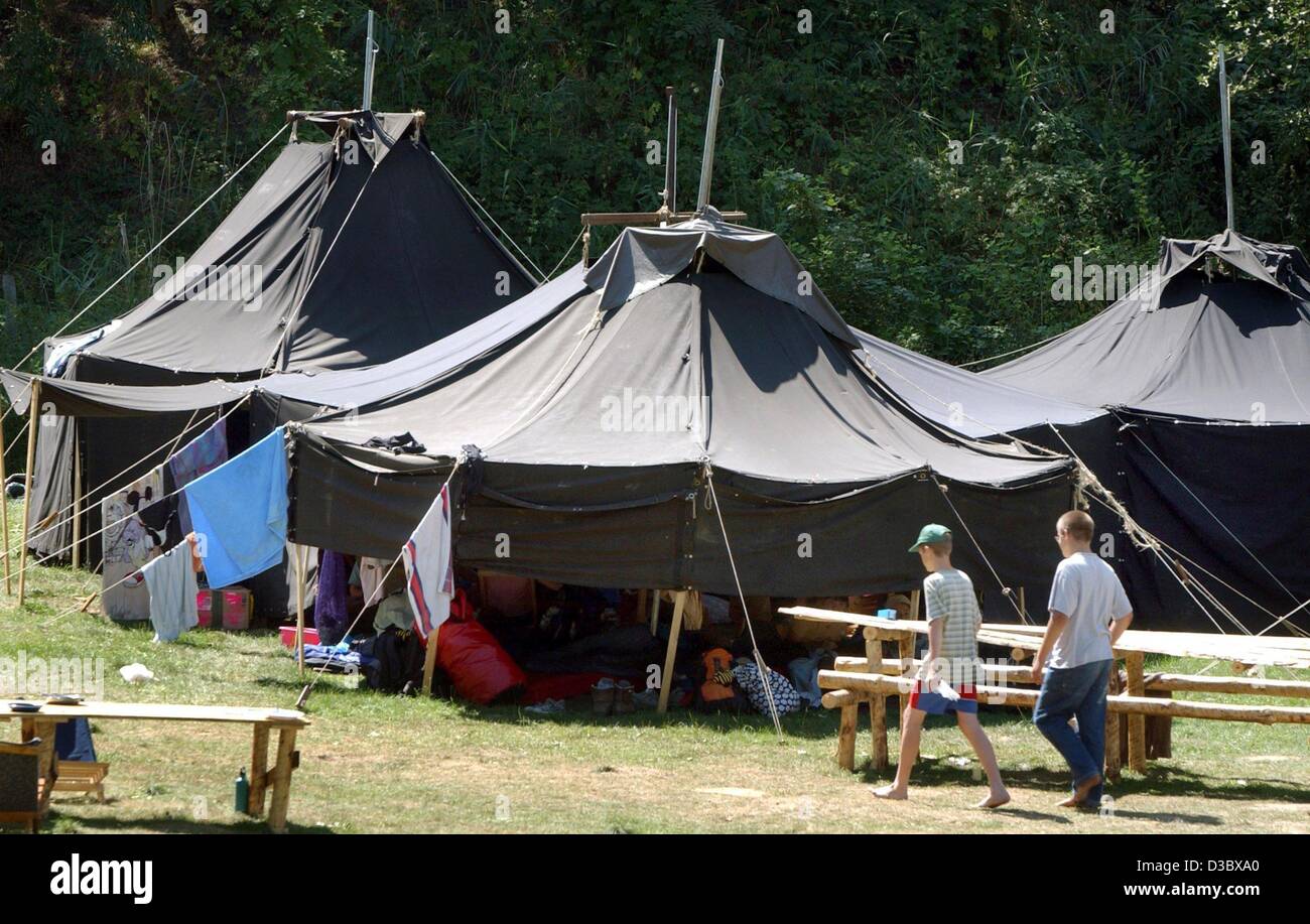 (dpa) Two boys walk past a group of tents during a camp meeting of