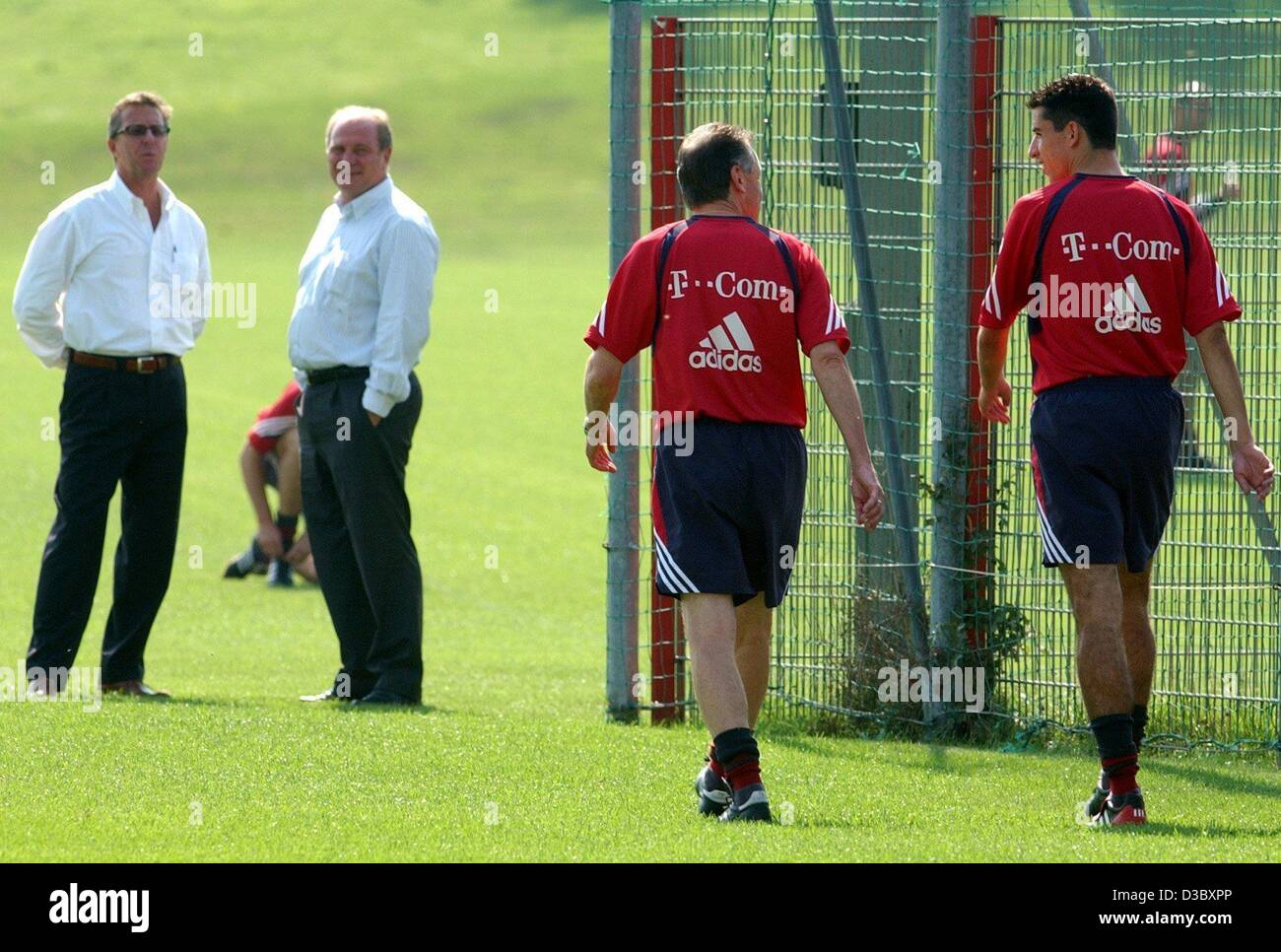 (dpa) - The coach of the soccer club FC Bayern Munich, Ottmar Hitzfeld (2nd from R) and the new Bayern player Roy Makaay from the Netherlands walk across the pitch during Makaay's first training session in Munich, 7 August 2003. In the background Bayern manager Uli Hoeness (2nd from L) and Makaay's  Stock Photo