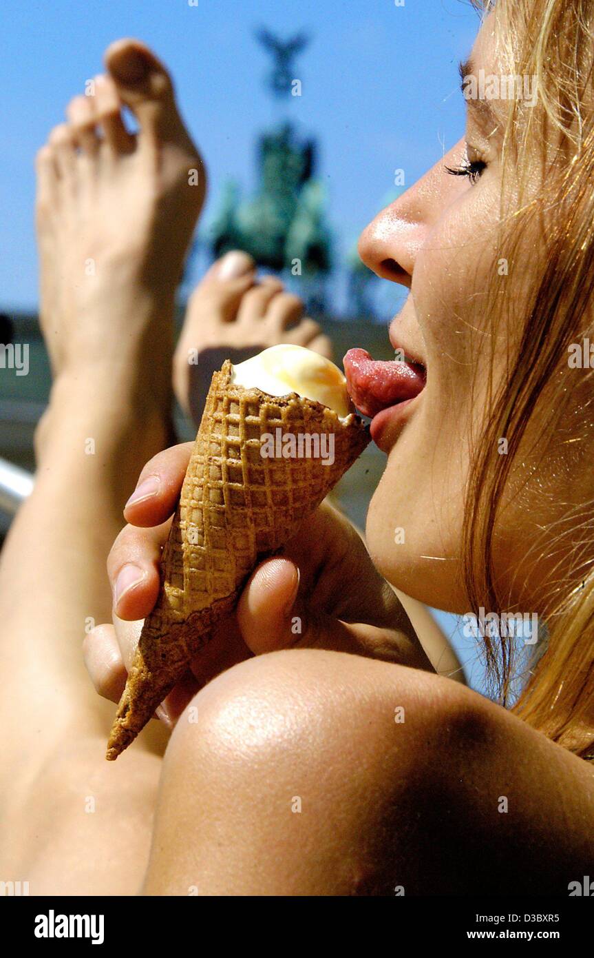 (dpa) - A young woman savours her ice cream on a bench in front of the Brandenburg Gate in Berlin, 7 August 2003. Temperatures climbed up to almost 40 degrees Celsius in various parts of Germany again. Stock Photo