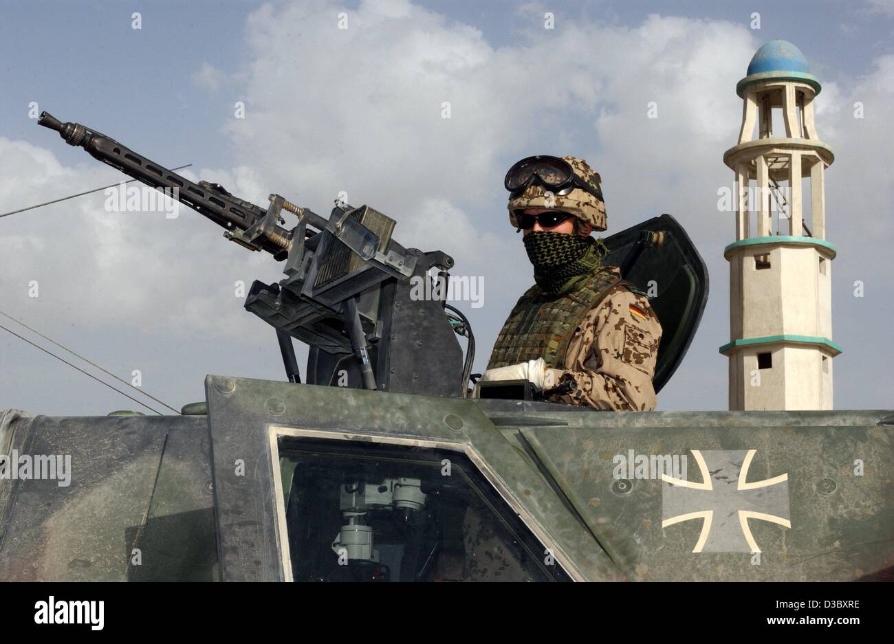 (dpa) - A Bundeswehr soldier of the International Security Assistance Force (ISAF) patrols in an armoured Dingo in front of a minaret the streets of Karteparwan, a northern district of Kabul, Afghanistan, 4 August 2003. Next Monday, 11 August, Germany and the Netherlands will hand over leadership of Stock Photo