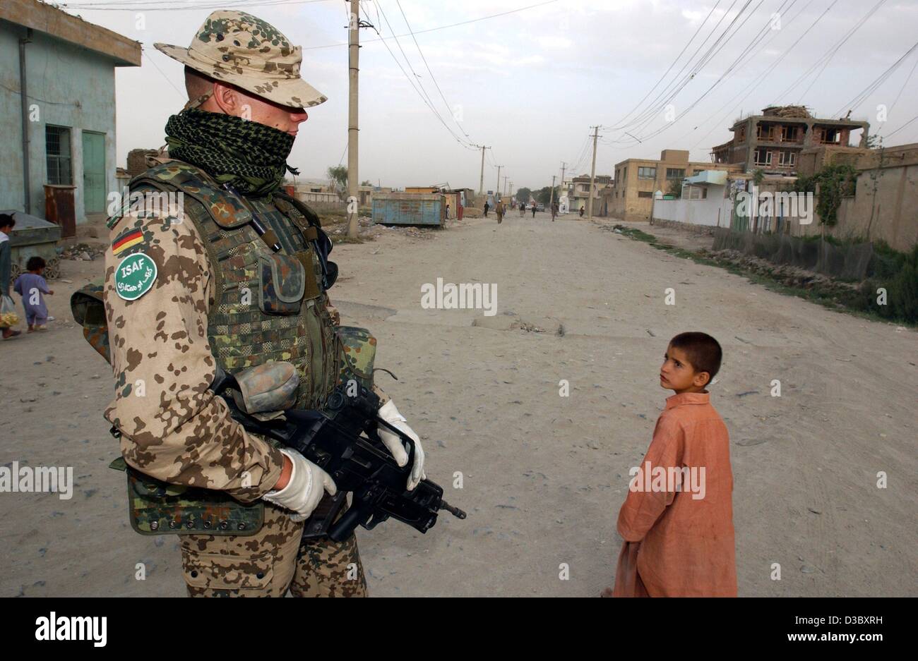 (dpa) - A Bundeswehr soldier of the International Security Assistance Force (ISAF) with a machine gun in his hands patrols the streets of Karteparwan, a northern district of Kabul, Afghanistan, 4 August 2003. Next Monday, 11 August, Germany and the Netherlands will hand over leadership of the ISAF c Stock Photo