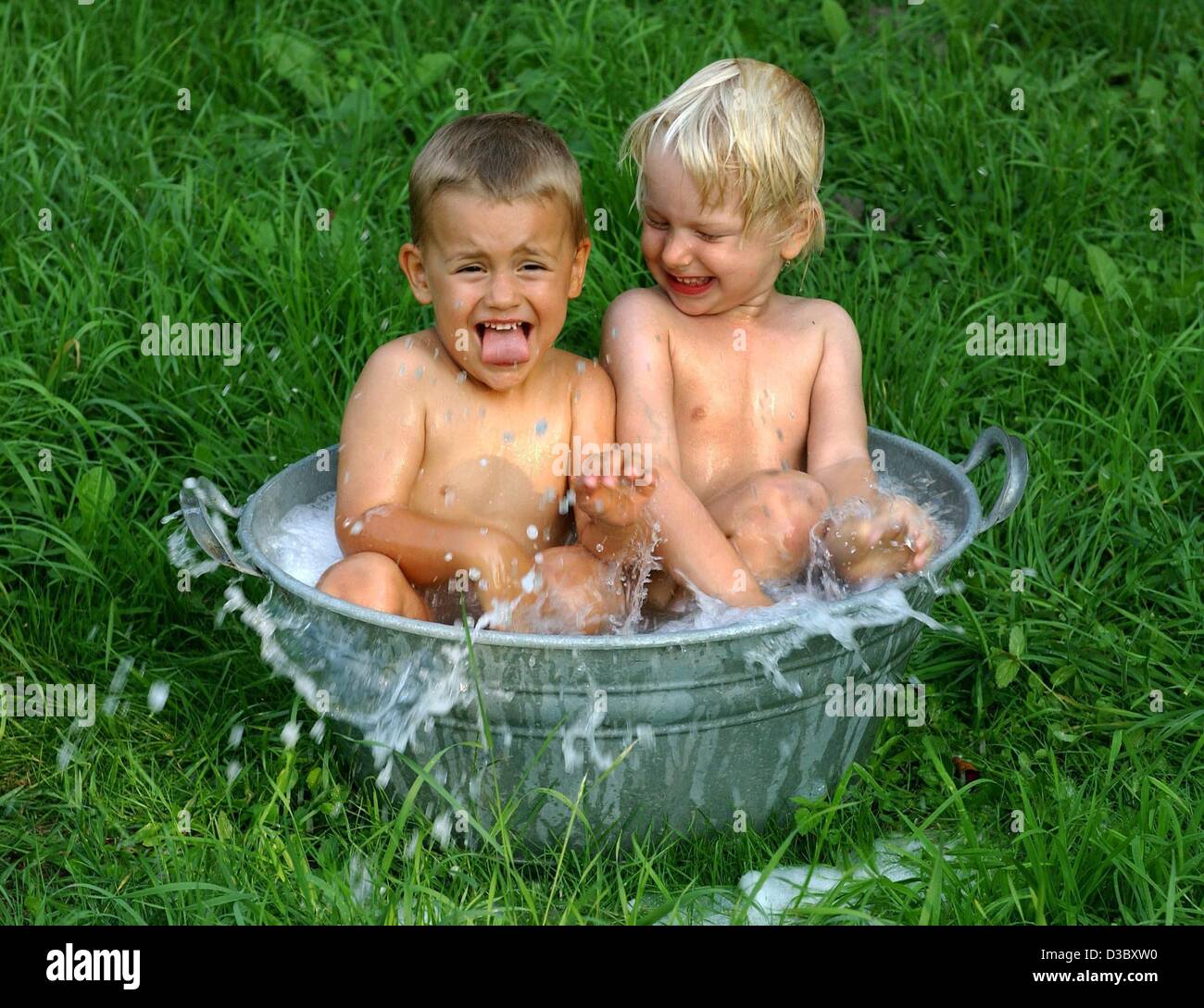 (dpa) - Viktoria and Damian (L) have fun taking a bath in a mini tub on a lawn in Frankfurt Oder, eastern Germany, 6 August 2003. Forecasters were again predicting the year's record temperature would be broken but the elusive all time German record of 40.2 degrees Centigrade remained intact. Stock Photo