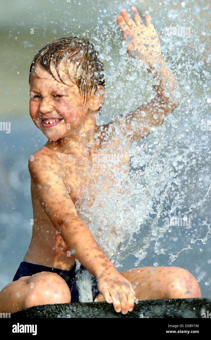 (dpa) - The six-year-old Leon enjoys the splashing water while sitting in the basin of a fountain in Magdeburg, Germany, 3 August 2003. A heat wave of up to 40 degrees Centigrade is forecast for southwestern Germany. Stock Photo