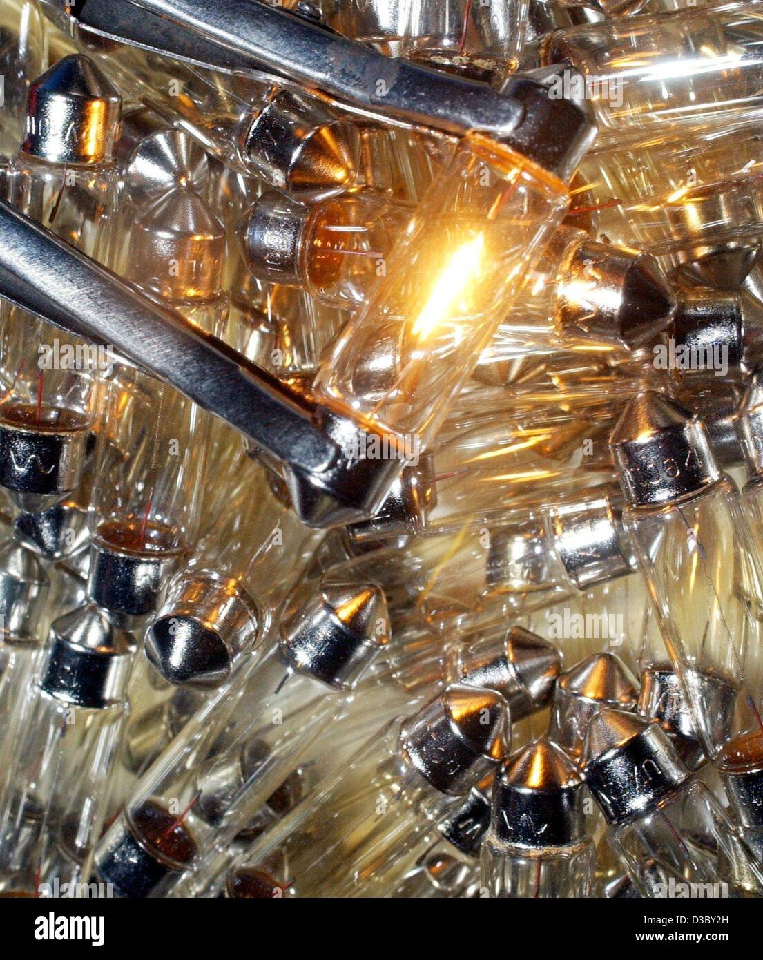 (dpa) - A low voltage light bulb glows in front of a heap of same light bulbs at the production site of the light bulb manufacturer Narva-Golux in Oberweissbach, Germany, 11 June 2003. The small light bulbs are used for signal lights, illuminations and glass light decorations. Stock Photo