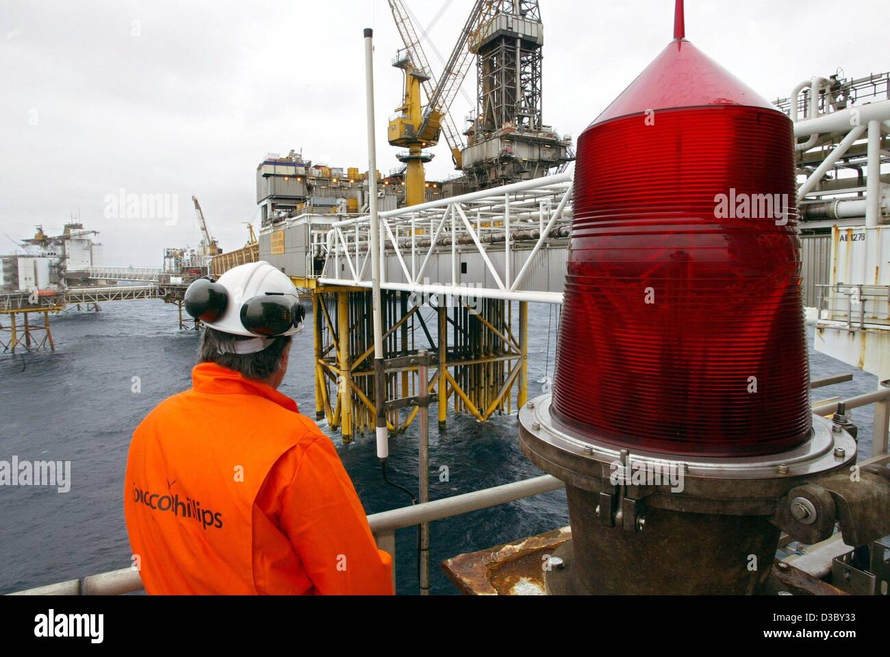 (dpa) - A worker stands on the gas and oil rig in the North Sea, about 250 km offshore of Stavanger, Norway, 5 July 2003. On the right a huge position light for ships. The platform belongs to the Ekofisk field complex, which comprises the oil and gas rigs Ekofisk, Eldfisk, Embla and Tor. The workers Stock Photo