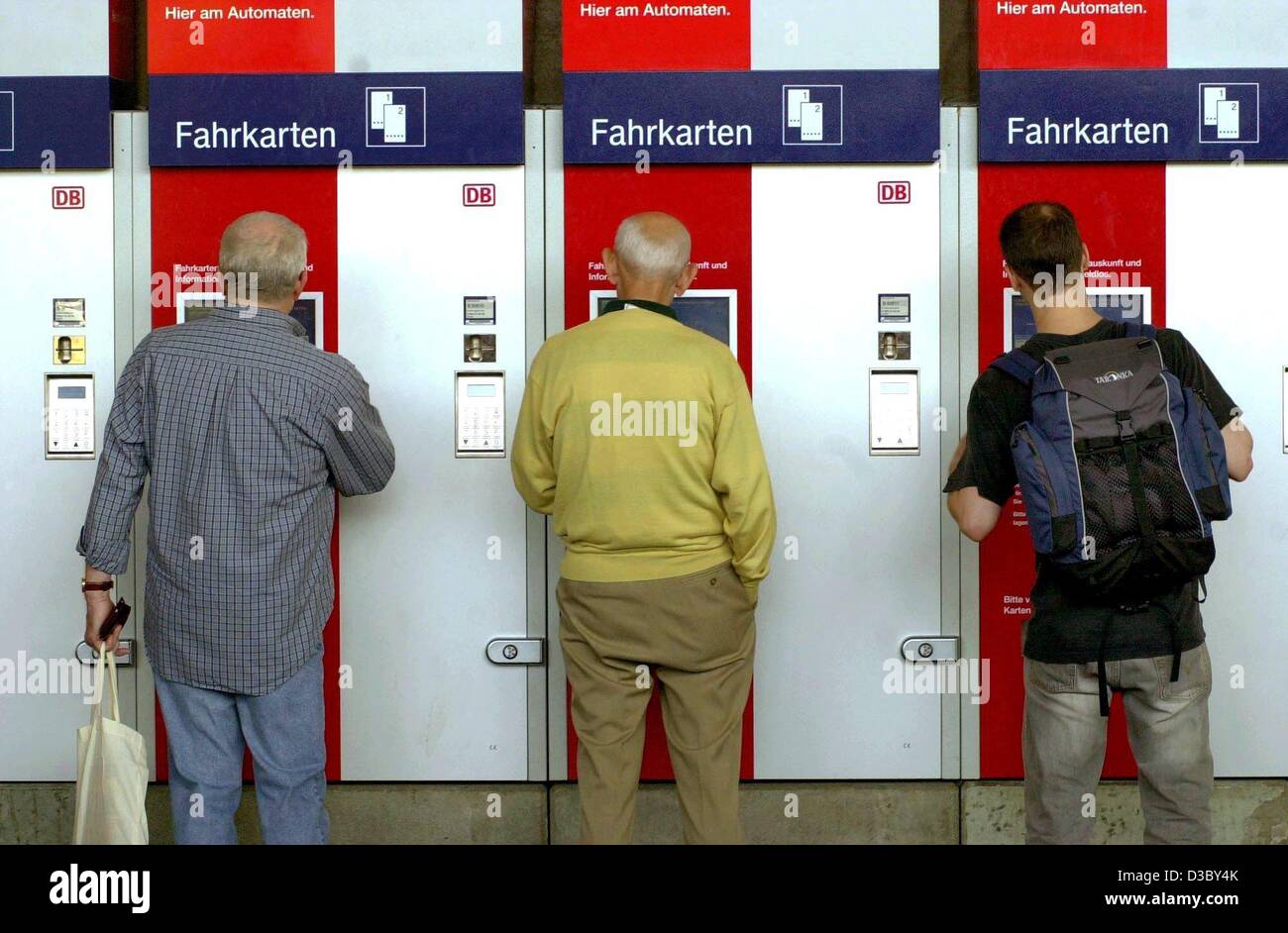 (dpa) - Travellers buy railway tickets (Fahrkarten) from ticket vending machines at the central station in Wuerzburg, Germany, 1 August 2003. The German railway corporation Deutsche Bahn AG introduced new ticket prices taking effect today, 1 August 2003, after their last price system, which was intr Stock Photo