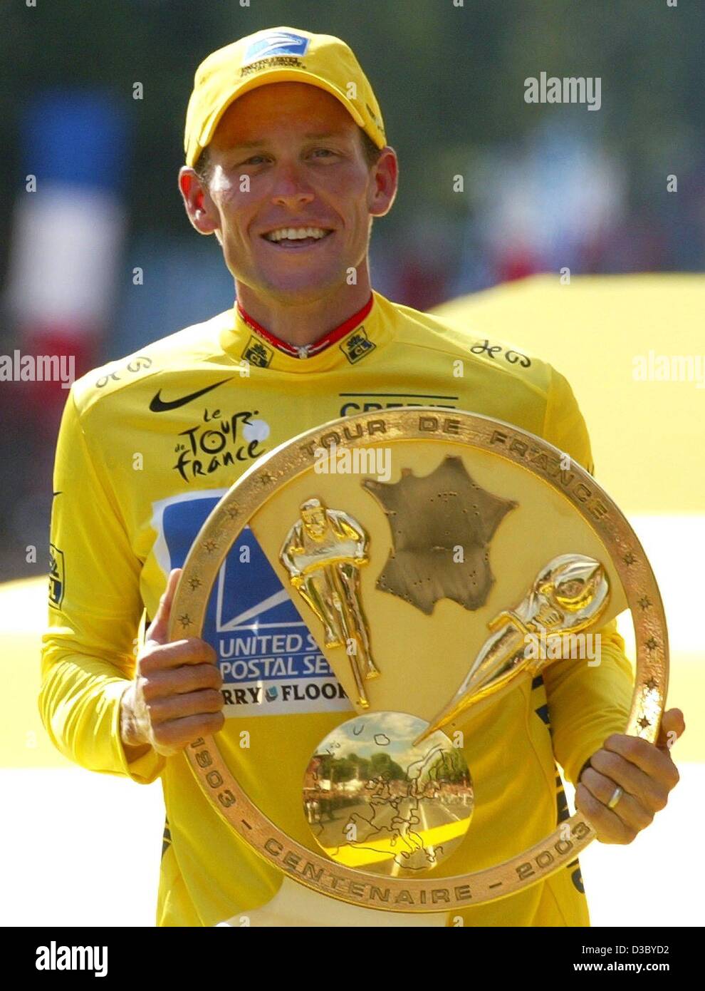 (dpa) - US Postal-Berry Floor's Lance Armstrong from the US, wearing the overall leader's yellow jersey, smiles as he holds his award in front of him while he stands on the podium after the 20th stage of the 2003 Tour de France cycling race, in Paris, 27 July 2003. Armstrong became the second rider  Stock Photo