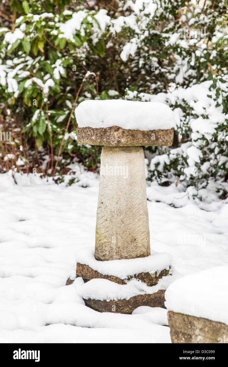 Snow covered ornamental stone bird bath in an English garden in winter Stock Photo