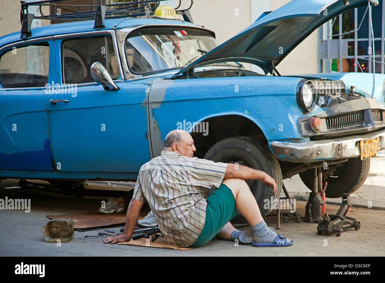 Cuban car mechanic repairing 1950s vintage American car / Yank tank / taxi on street in Havana, Cuba, Caribbean Stock Photo