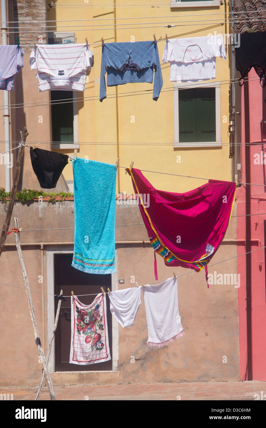 Washing hanging on lines in square hanging outside typical yellow painted house Burano Island Venice Veneto Italy Stock Photo