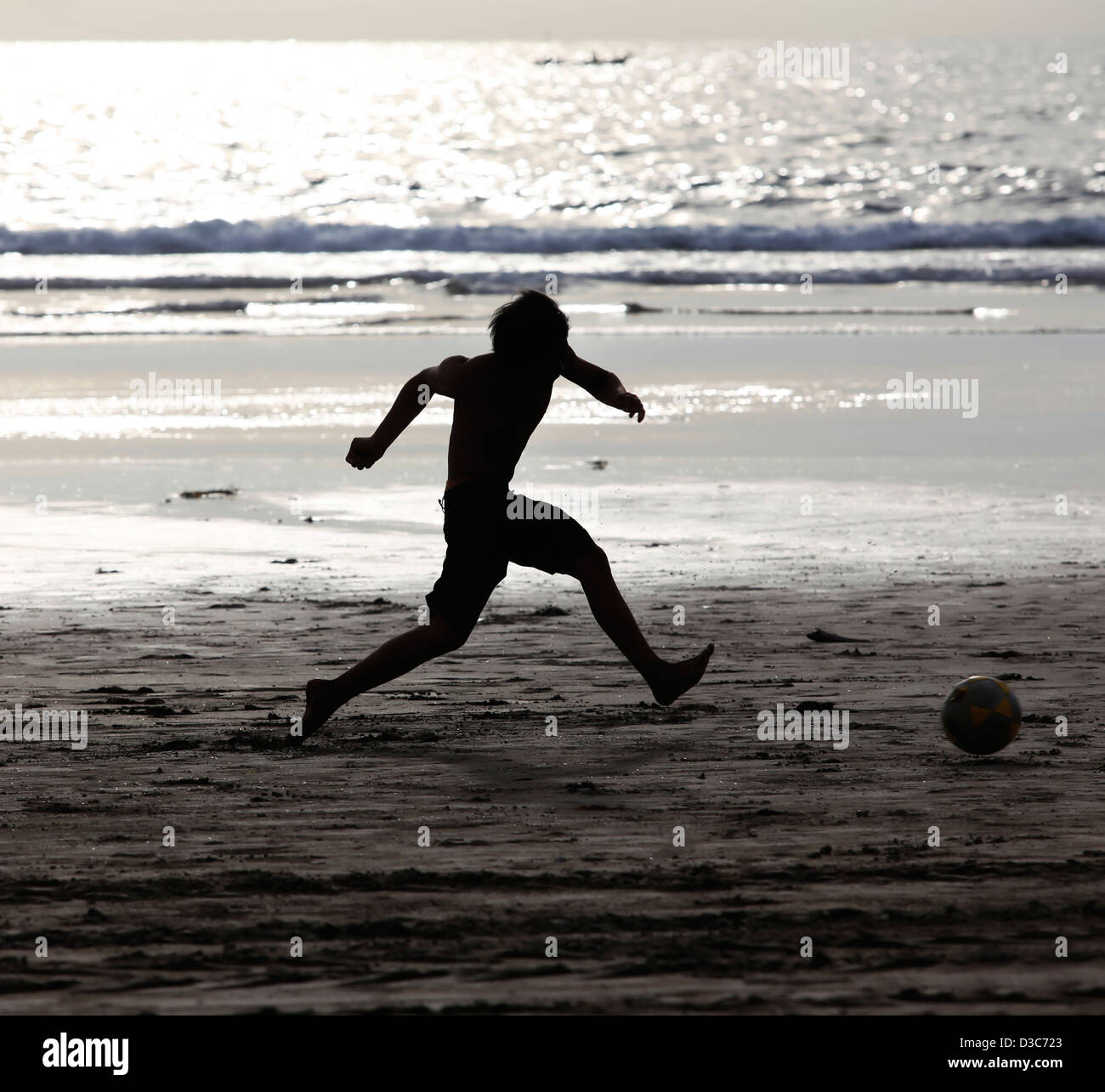 Young boy having fun on the beach playing football Stock Photo Alamy