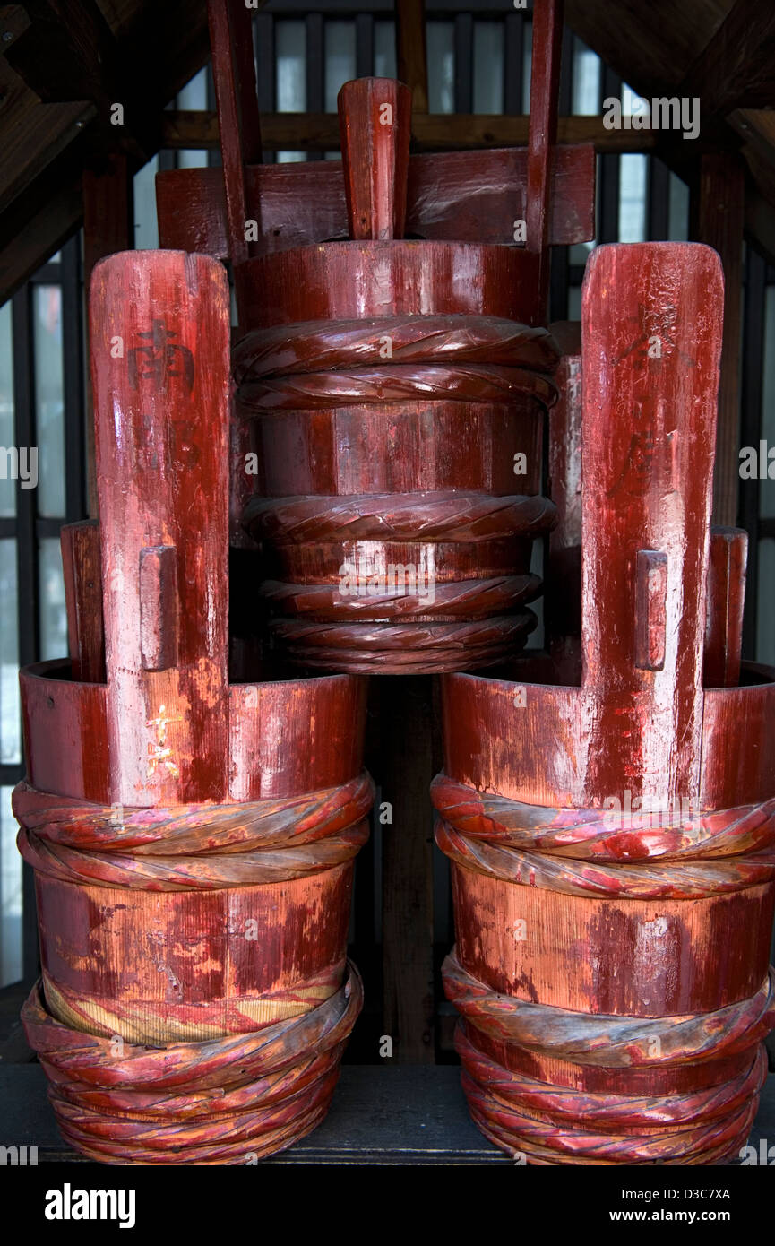 A pattern composition of three stacked traditional wooden Japanese fire buckets painted red. Stock Photo