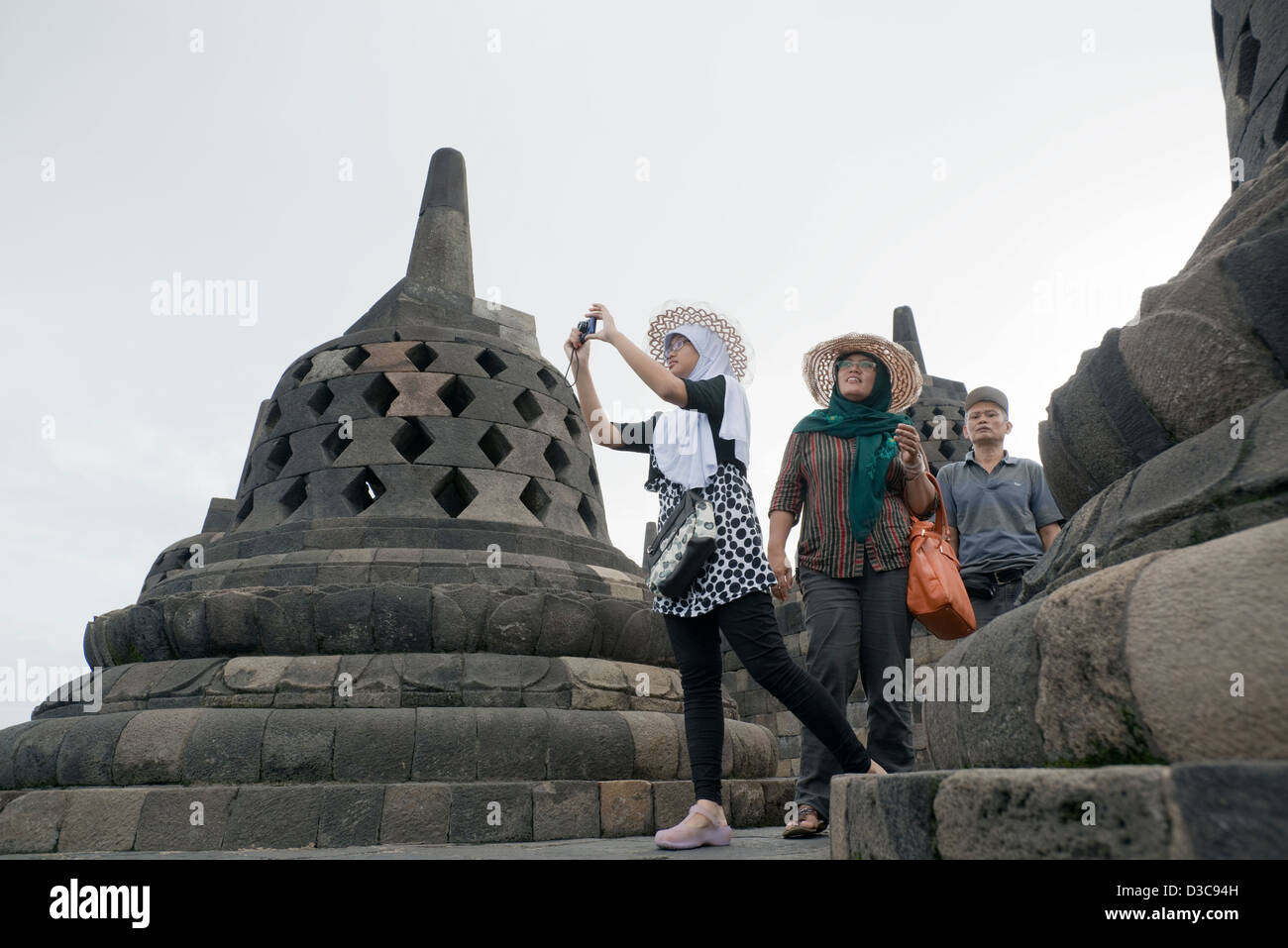 A young Indonesian woman takes a photo at the Borobudur Buddhist Temple in Java, Indonesia Stock Photo