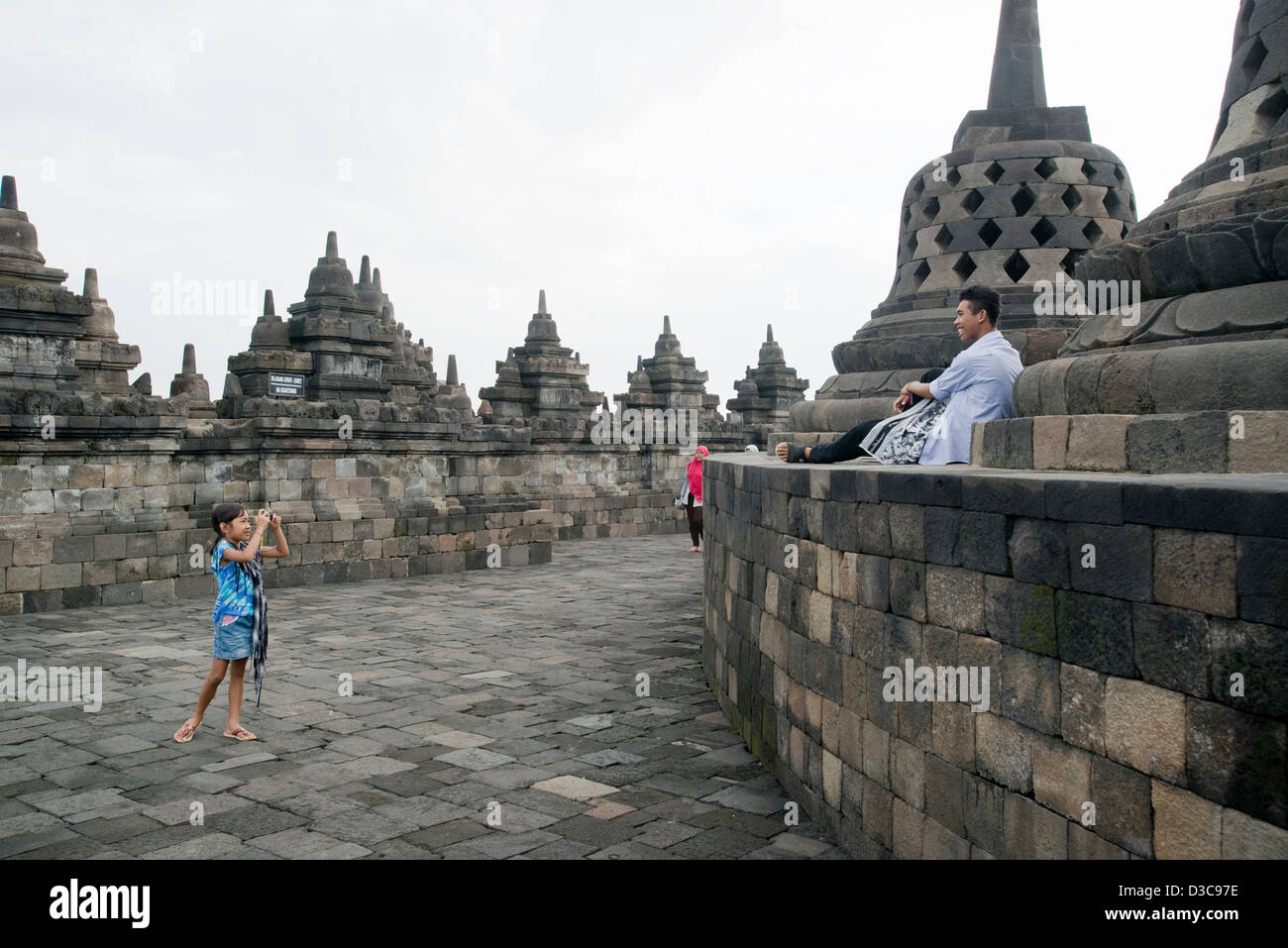 A small child takes a picture of her father at the Borobudur Buddhist Temple in Java, Indonesia Stock Photo