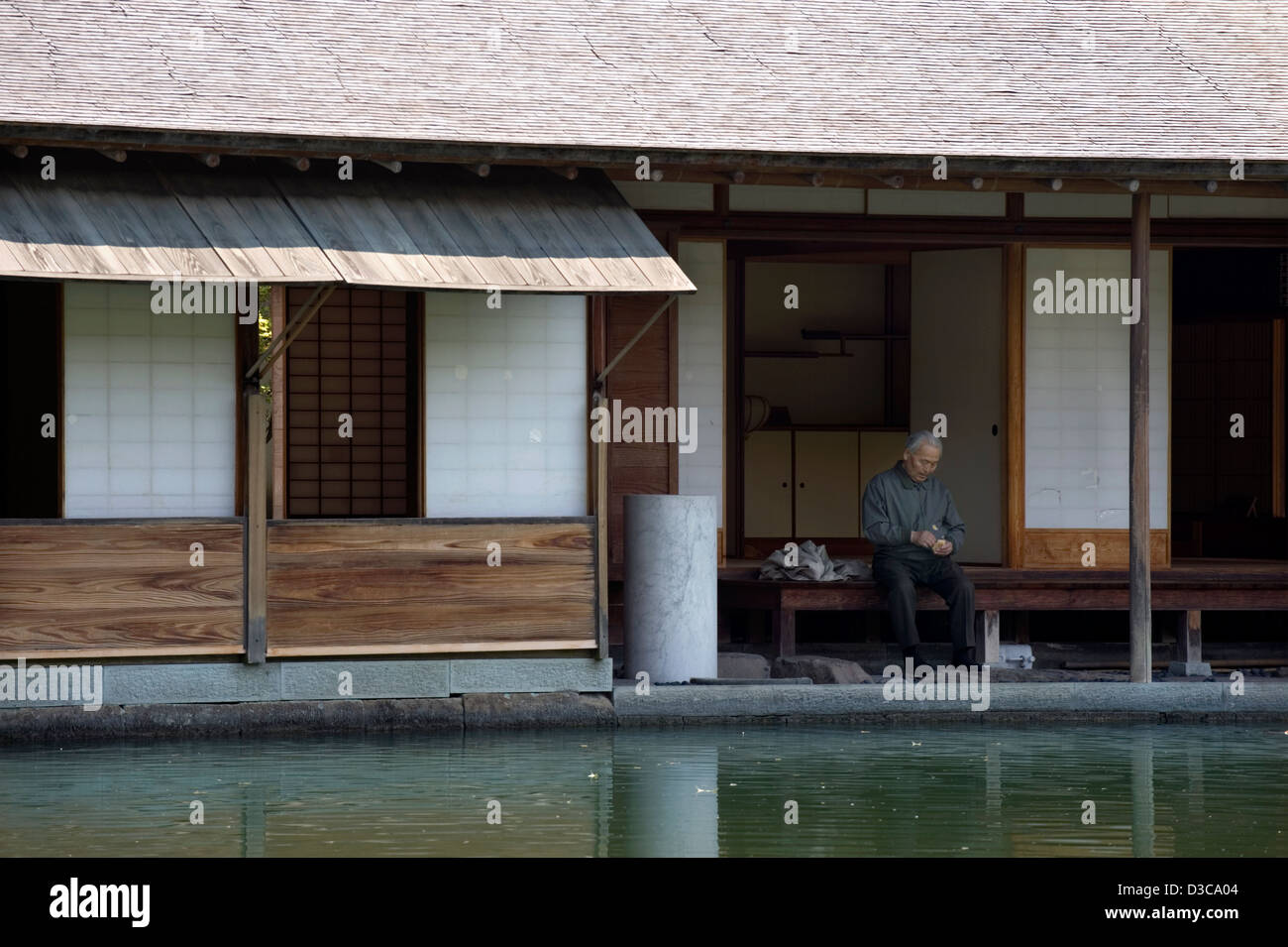 Peaceful, tranquil atmosphere of elderly man relaxing on terrace deck beside pond of historic Yokokan villa in Fukui, Japan. Stock Photo