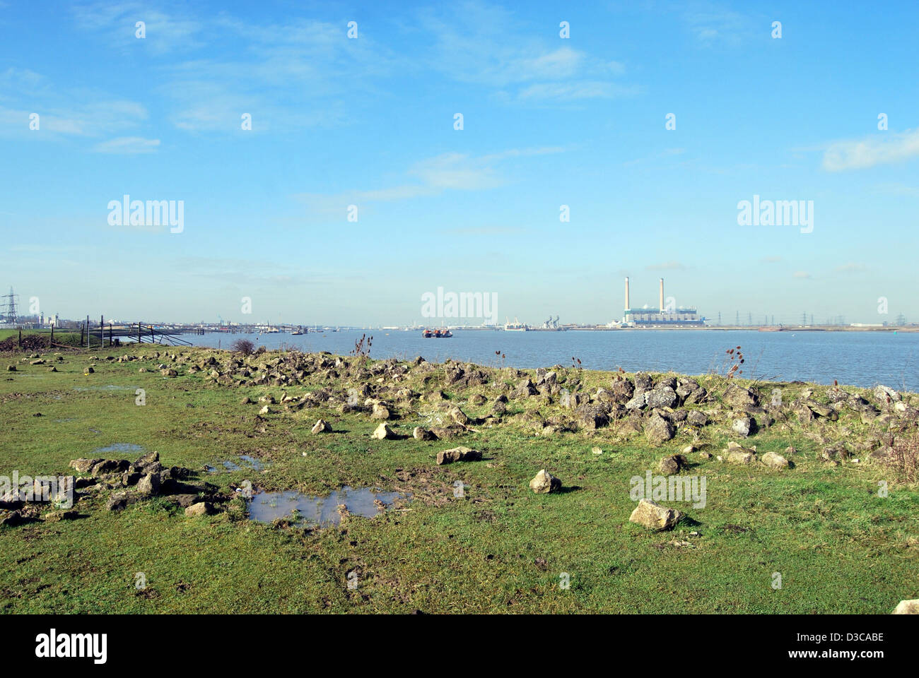 A  view of the River Thames from Gravesend in Kent showing Tilbury power station and rocks in a flooded field in the foreground. Stock Photo
