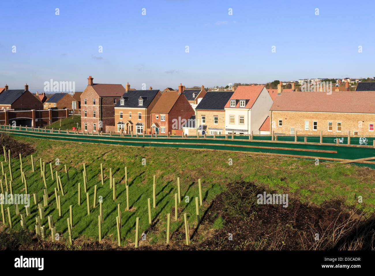 Brand new houses by an embankment with trees planted for noise reduction Stock Photo