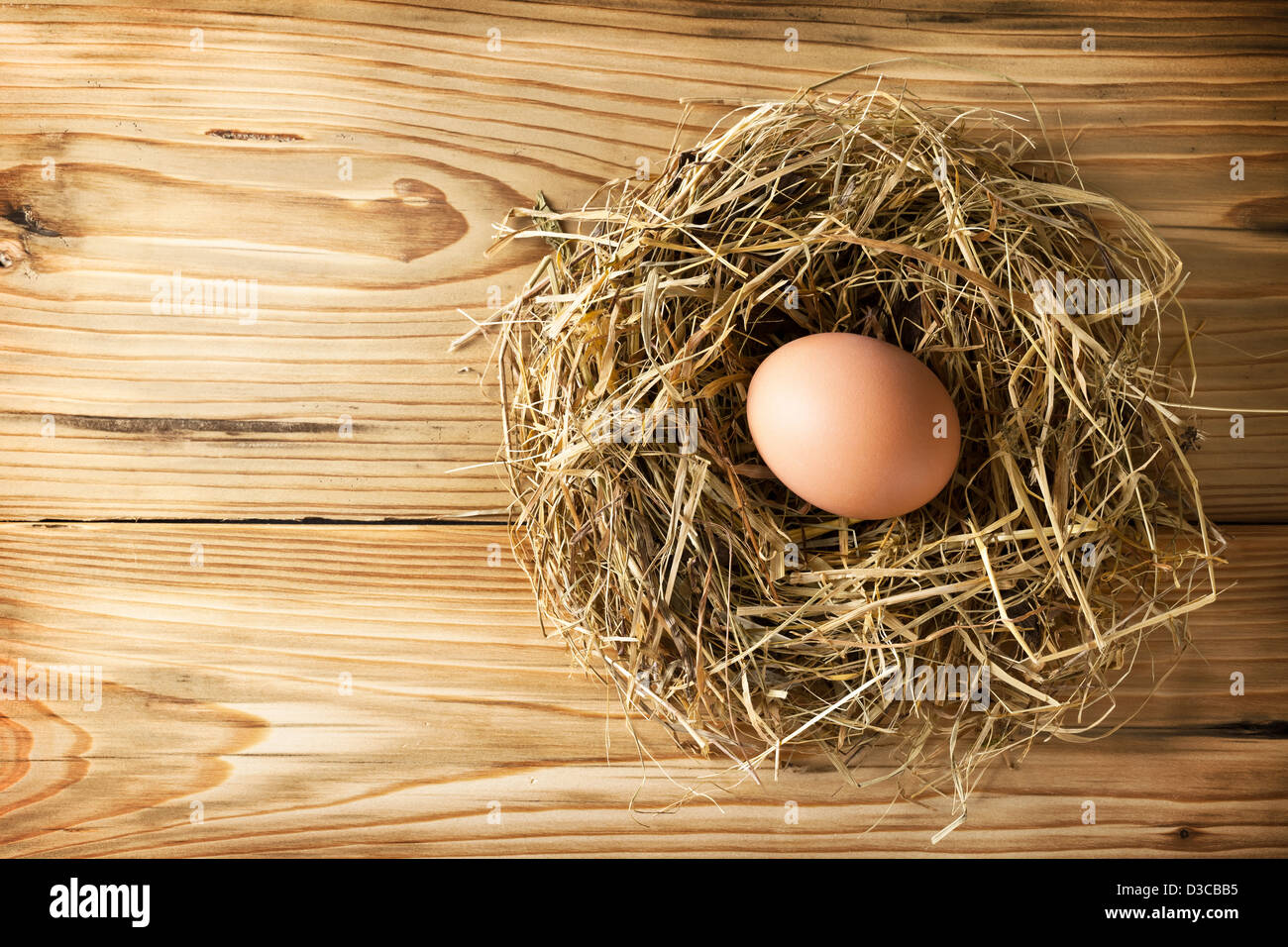 Egg in hay nest on wooden table background. Top view Stock Photo - Alamy