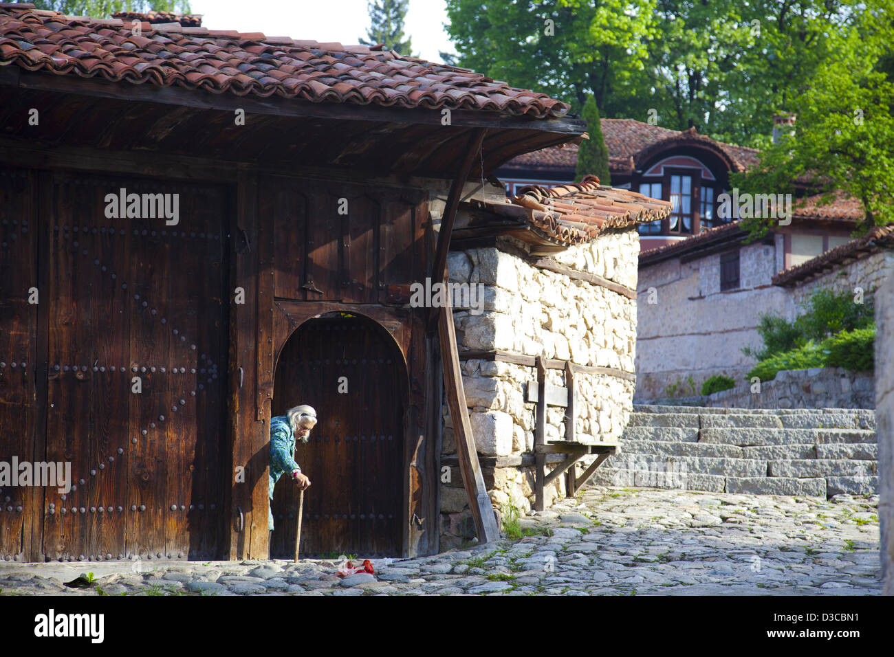 Bulgaria, Europe, Koprivshtitsa, Old Town, Dimcho Debelianov Street, Kableshkov House In The Background, Old Woman. Stock Photo