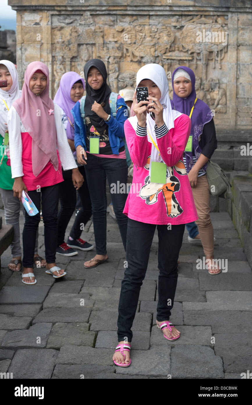 A young Indonesian woman wearing a Hijab takes a photo at the Borobudur Buddhist Temple in Java, Indonesia Stock Photo