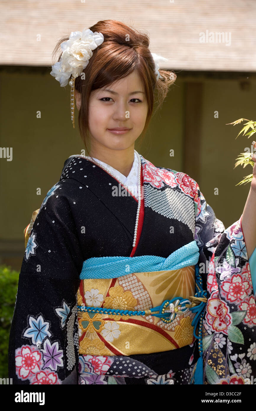 Cute, 20-something Japanese girl wearing traditional furisode long-sleeve kimono with spring flower design poses in Fukui, Japan Stock Photo