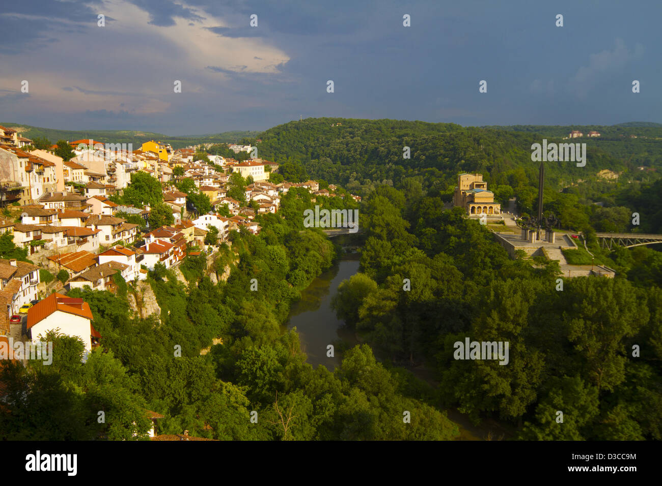 Bulgaria, Veliko Tarnovo, Hillside Houses Towering Above The Yantra River, Stormy Weather With Rainbow At Dusk. Stock Photo