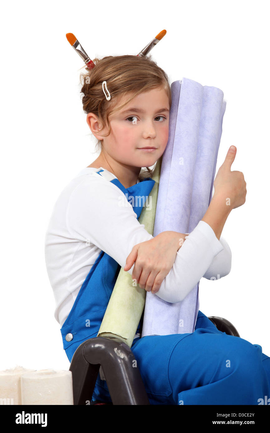 little girl wearing painter&rsquo;s overalls and holding wallpapers Stock
