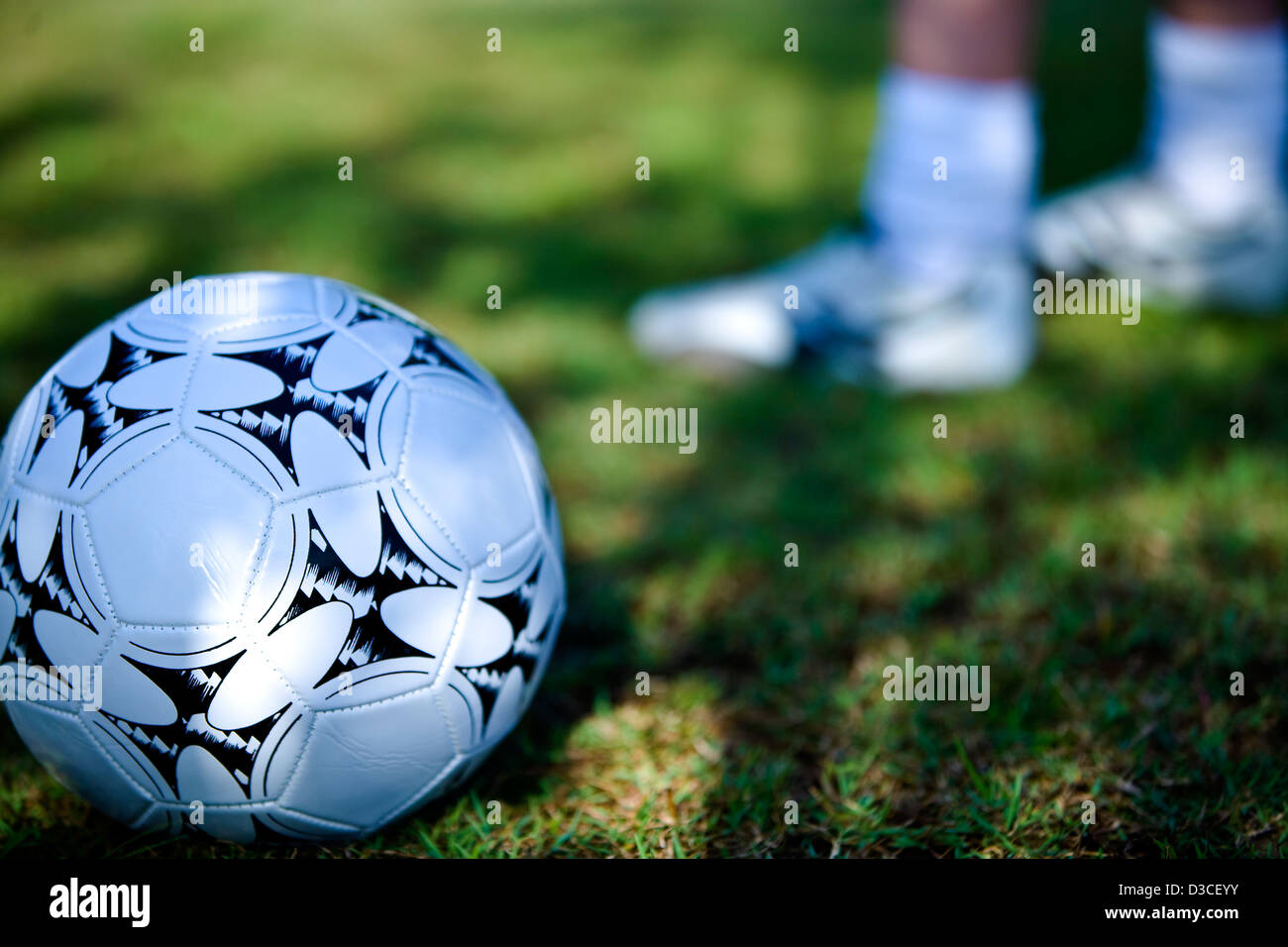 Sports field with ground level image of a football and person standing in the background Stock Photo