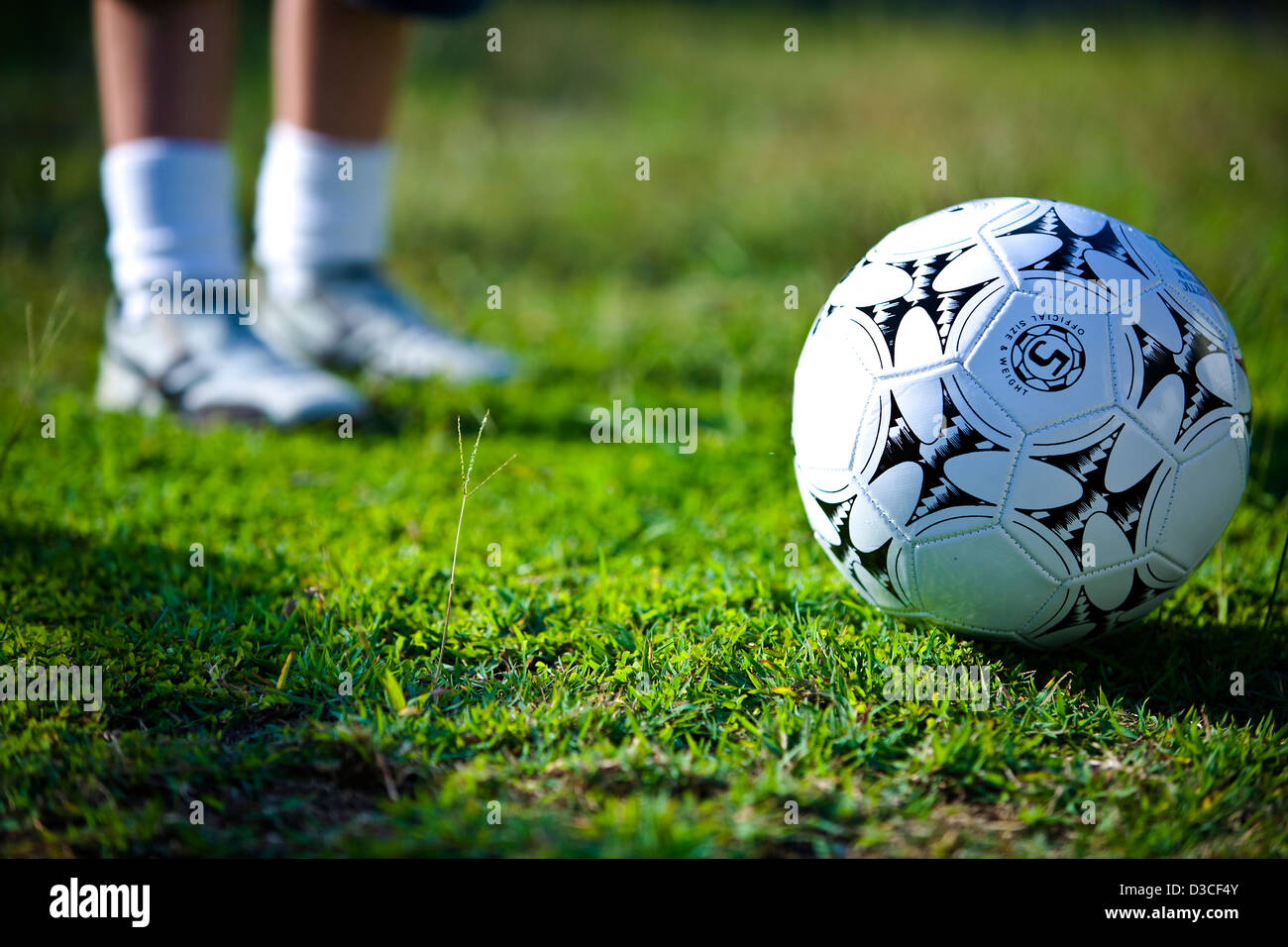 Sports field with ground level image of a football and person in background Stock Photo
