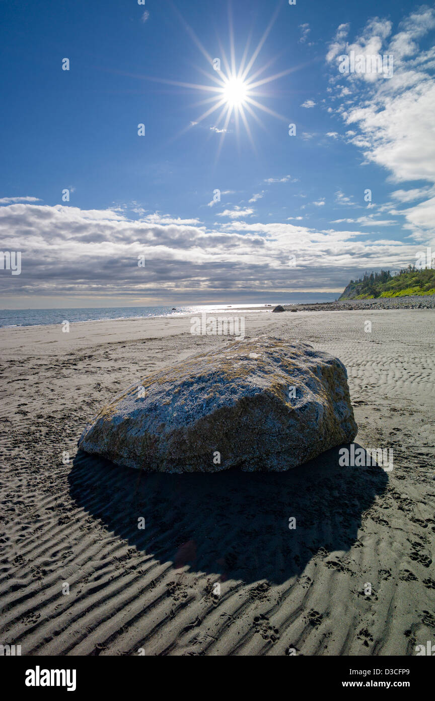 Sunburst over large lone boulder, Bishop Beach, Homer, Alaska, USA Stock Photo