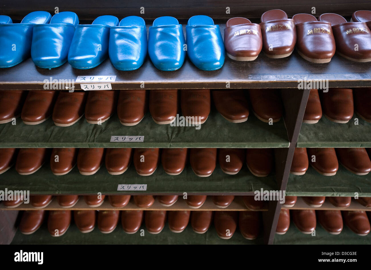 Rows of neatly arranged blue and brown slippers in a getabako (shoe cabinet) at a Taisho Period school in Matsumoto, Japan. Stock Photo