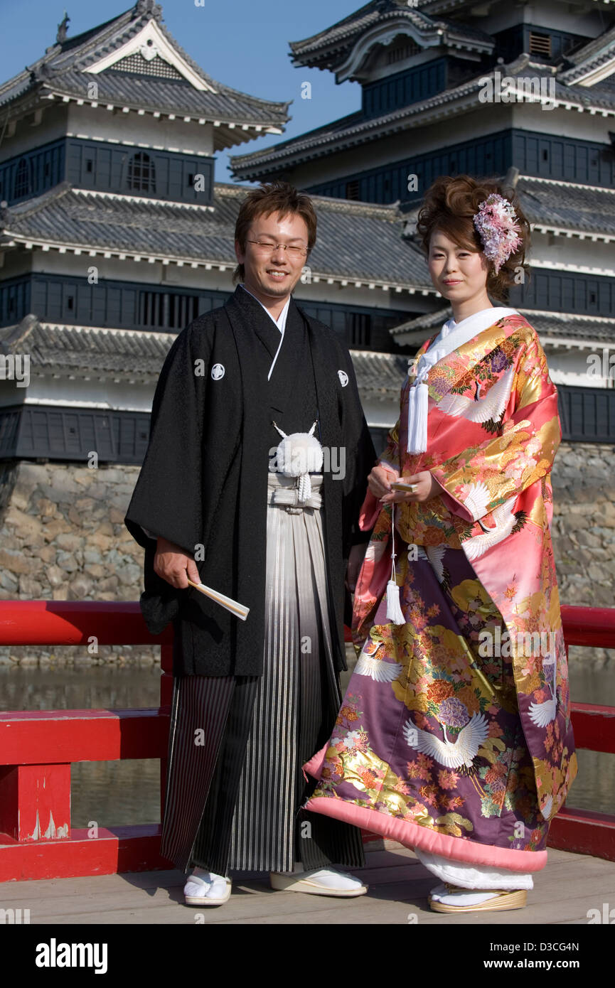 Wedding couple wearing traditional kimono pose in front of Matsumoto Castle on a sunny day. Stock Photo