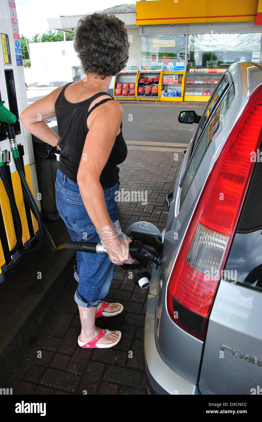 A woman filling up her car with fuel at a service station Stock Photo