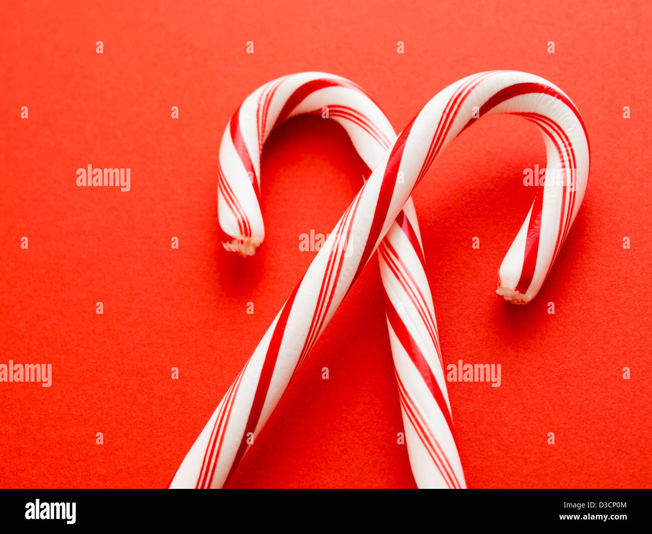 White and red peppermint candy canes on red background Stock Photo - Alamy