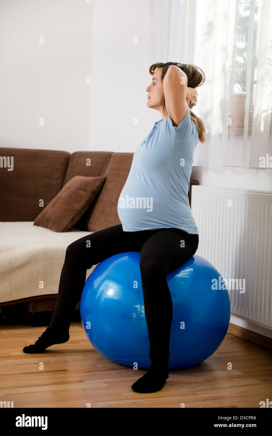 Pregnant woman exercising with fit ball at home Stock Photo