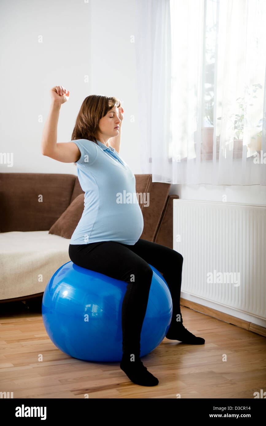 Pregnant woman exercising with fit ball at home Stock Photo