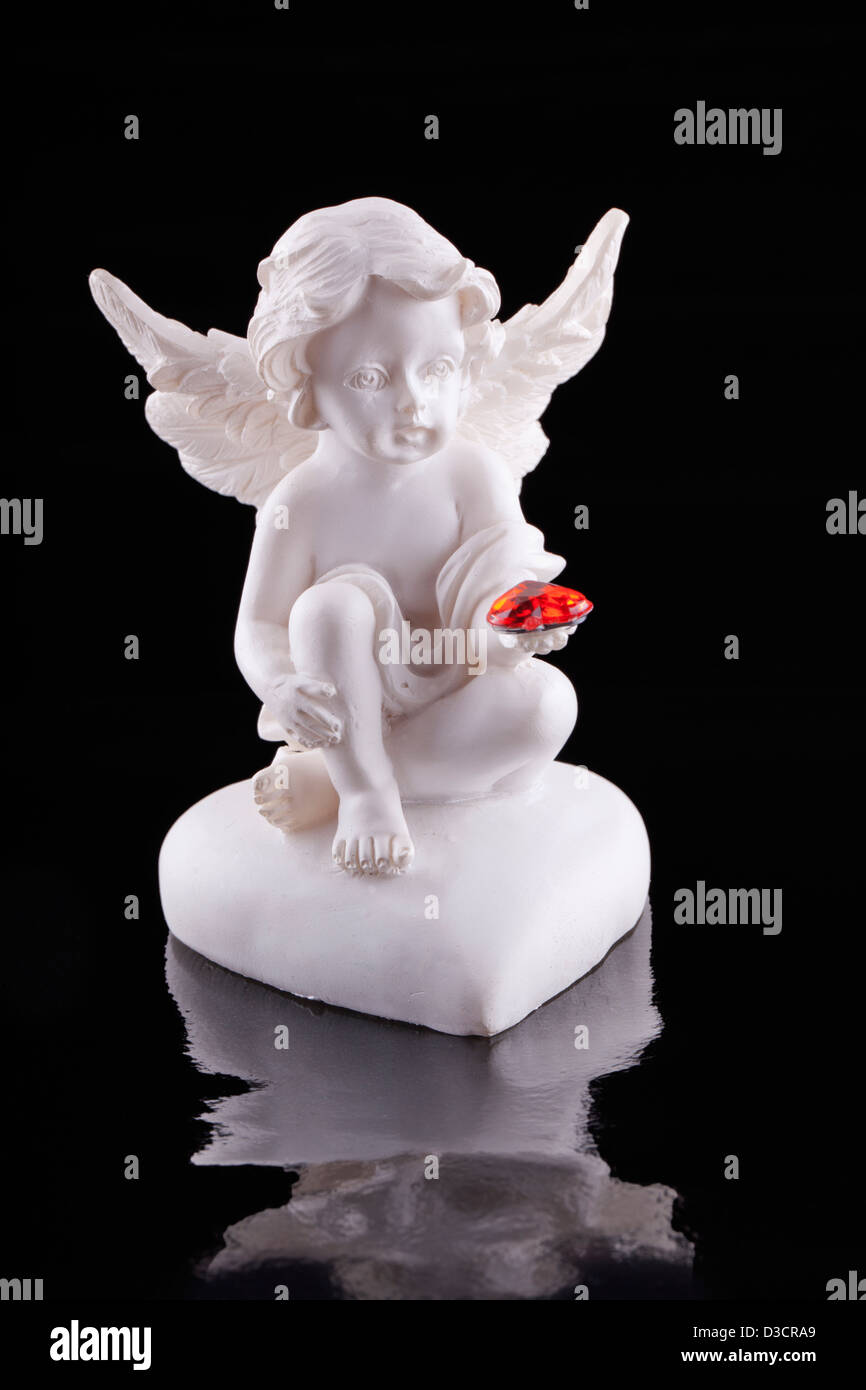 Close up of a little statue of an angel with a red heart on the hand Stock Photo