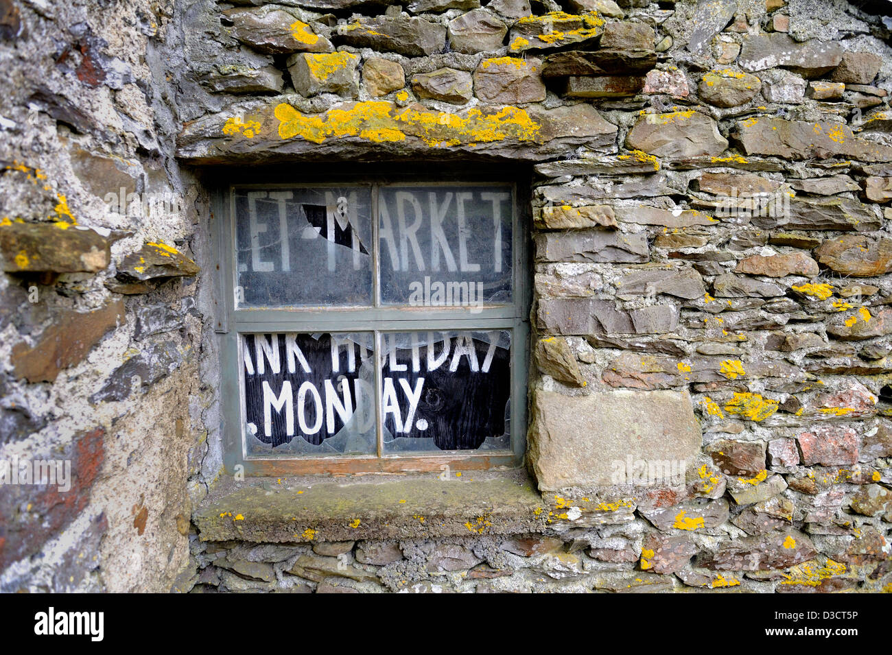Boarded up window using a market day sign to stop intruders and weather entering this stone built house. Stock Photo
