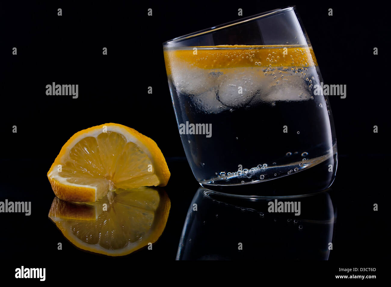 Gin and tonic or vodka and tonic with a slice of lemon over black Stock